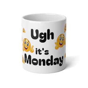 May include: White ceramic mug with the text "Ugh it's Monday" in black. The mug is decorated with yellow smiley face emojis with thumbs up and peace signs.
