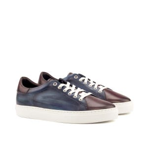May include: A pair of low-top sneakers featuring a gradient finish that transitions from a deep burgundy at the toe and heel to a brushed navy blue on the side panels. The shoes include white laces, silver-toned eyelets, and a thick white rubber sole.