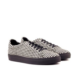 May include: A pair of low-top sneakers featuring a black and white houndstooth pattern across the upper fabric. The shoes include black laces, a black eyelet panel, and a solid black rubber sole that provides a contrast to the patterned textile.