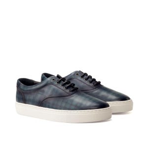 May include: A pair of low-top sneakers featuring a dark blue and green plaid pattern on the leather upper. The shoes have black laces, metal eyelets, and a thick white rubber sole. The design includes a rounded toe and a padded collar.