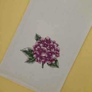 May include: White kitchen towel with an embroidered purple hydrangea flower design.