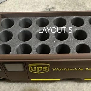 K&ouml;nnte beinhalten: Ein brauner UPS-LKW-f&ouml;rmiger Beh&auml;lter mit einem Raster aus kreisf&ouml;rmigen L&ouml;chern. Der Text "LAYOUT 5" ist oben sichtbar. Das UPS-Logo und "Worldwide Service" sind gelb auf der Seite aufgedruckt.