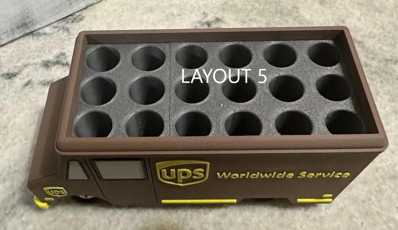 K&ouml;nnte beinhalten: Ein brauner UPS-LKW-f&ouml;rmiger Beh&auml;lter mit einem Raster aus kreisf&ouml;rmigen L&ouml;chern. Der Text "LAYOUT 5" ist oben sichtbar. Das UPS-Logo und "Worldwide Service" sind gelb auf der Seite aufgedruckt.