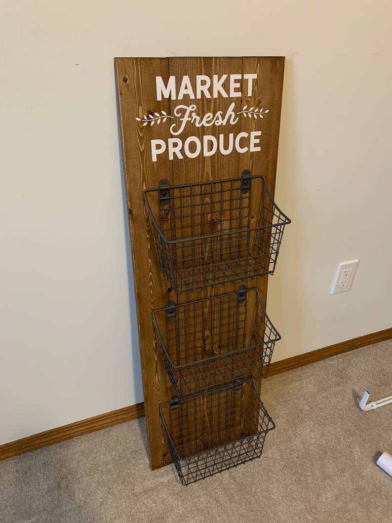 May include: A wooden wall-mounted organizer with the text "MARKET Fresh PRODUCE" and three wire baskets.