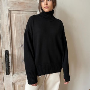 May include: A black turtleneck sweater with long sleeves and a ribbed hem.