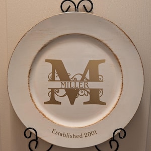 May include: White charger plate with a gold monogram "M" and the name "Miller" underneath. The plate also has the text "Established 2001" on the bottom.