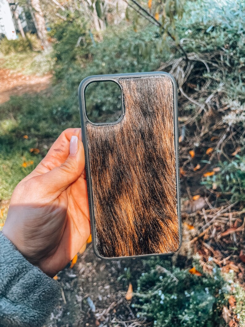 May include: A black phone case with a brown and black cowhide pattern.