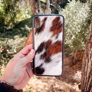 May include: A black phone case with a brown, white, and black cowhide pattern.