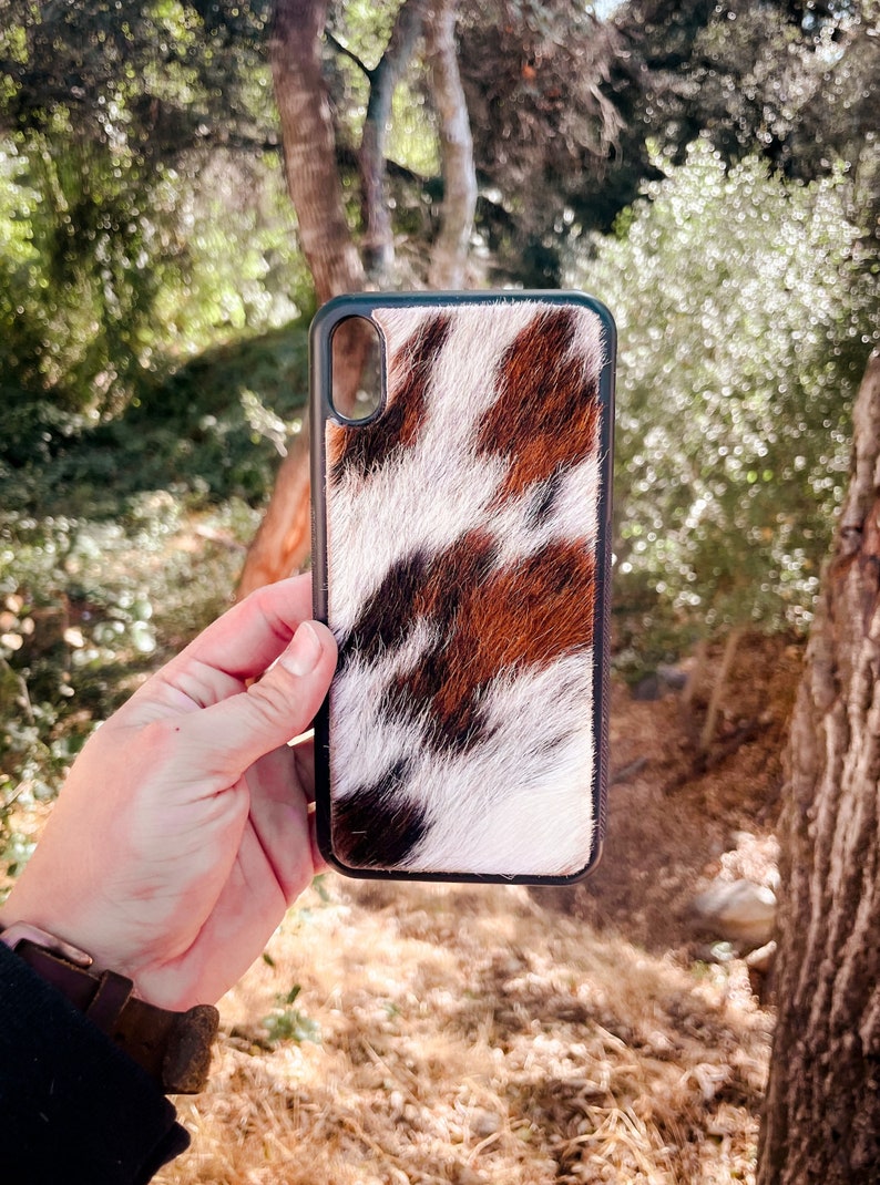 May include: A black phone case with a brown, white, and black cowhide pattern.