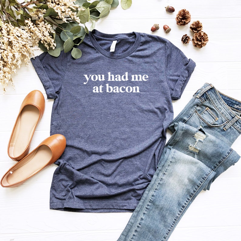 Pu&ograve; includere: Una maglietta blu navy con la scritta "You had me at bacon" in lettere bianche.