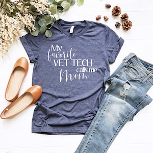 Puede incluir: Una camiseta azul marino con el texto "My favorite vet tech calls me mom" en letras blancas.