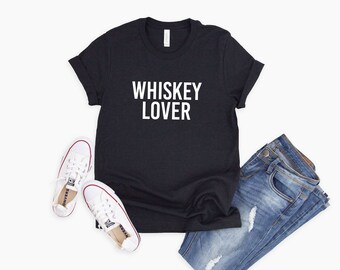 Peut inclure: T-shirt noir avec un texte blanc qui dit "Whiskey Lover". Le t-shirt est associé à un jean bleu et des baskets blanches.