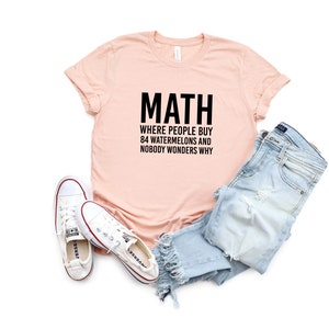 May include: A pink t-shirt with the text "MATH WHERE PEOPLE BUY 84 WATERMELONS AND NOBODY WONDERS WHY" printed in black.