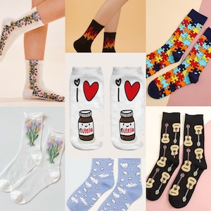 May include: A set of 10 pairs of colorful socks with various designs, including flowers, hearts, Nutella jars, puzzle pieces, guitars, and clouds. The socks are all white, black, blue, or orange.