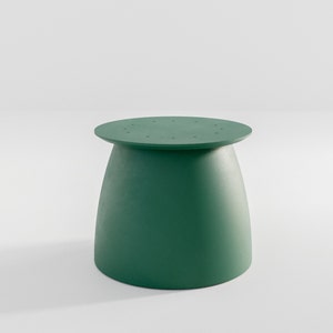 Pu&ograve; includere: Uno sgabello rotondo di colore verde con una base leggermente svasata. La parte superiore dello sgabello presenta un motivo circolare di piccoli fori.