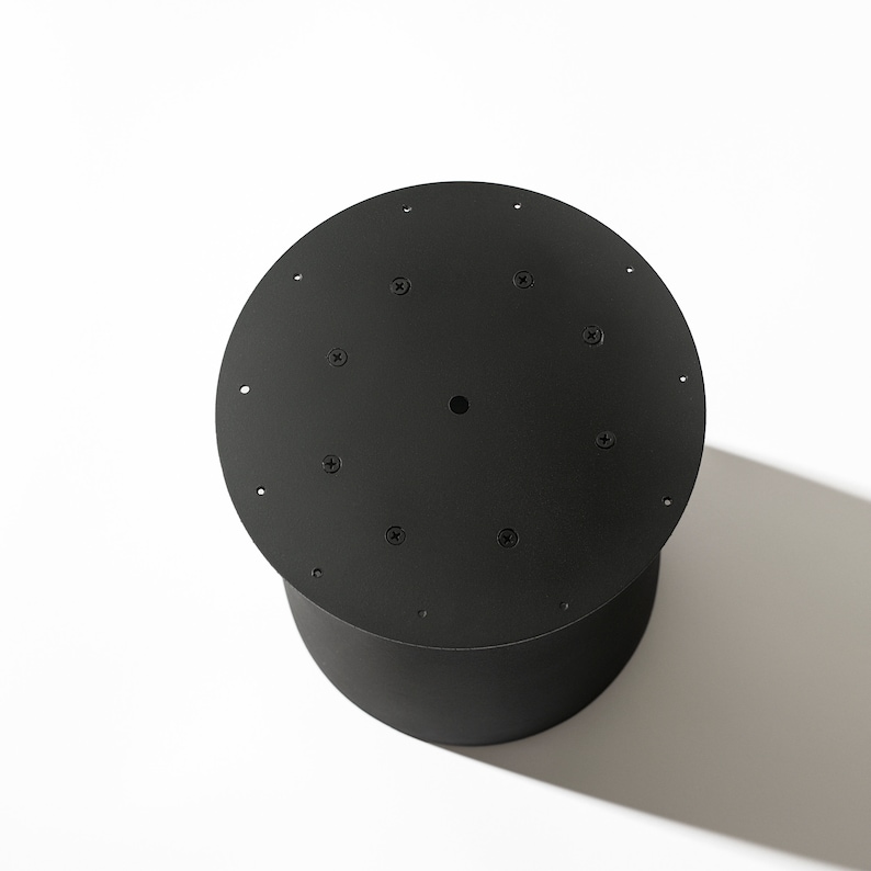 May include: Black metal round base with a hole in the center and multiple screw holes around the edge.