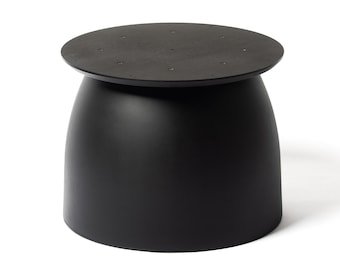 May include: A black, round,  table with a smooth, curved base. The table top is flat and has a slightly raised edge.