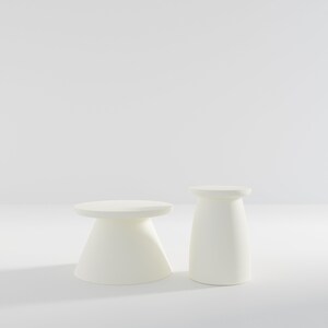 May include: Two white, round, pedestal-style side tables. The table on the left is slightly larger than the table on the right.