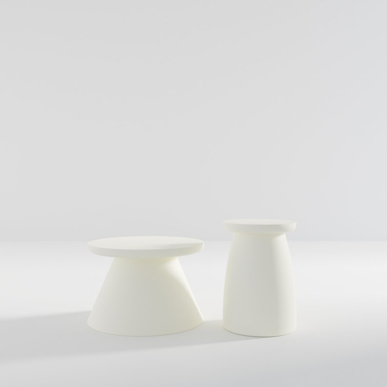 May include: Two white, round, pedestal-style side tables. The table on the left is slightly larger than the table on the right.