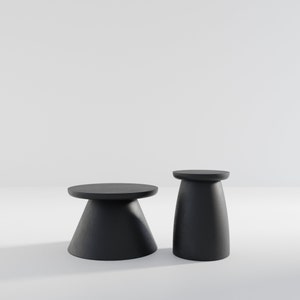 May include: Two black, round, pedestal tables. The larger table has a wider base and a smaller top. The smaller table has a narrower base and a larger top.
