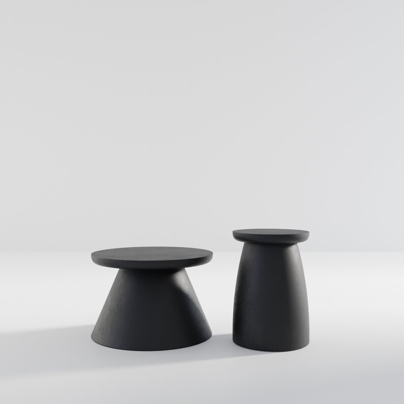 May include: Two black, round, pedestal tables. The larger table has a wider base and a smaller top. The smaller table has a narrower base and a larger top.