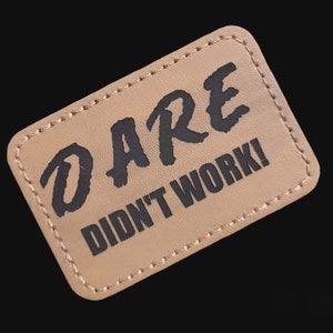 May include: Tan leather patch with black stitching and the text "DARE DIDN'T WORK!" in a bold, handwritten font.