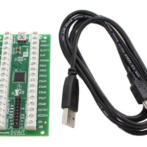 May include: A green UltiMarc I-PAC circuit board with multiple connection points and a black USB cable. The board has various labels and a central processor. The USB cable is black and has a standard USB connector.