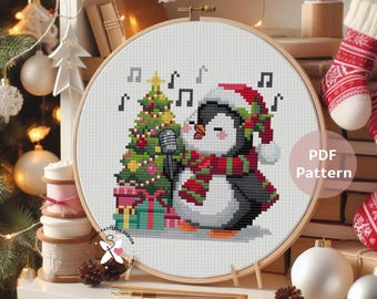 May include: A cross-stitch pattern featuring a penguin wearing a Santa hat and scarf, singing into a microphone next to a Christmas tree and presents. The text "PDF Pattern" is visible.