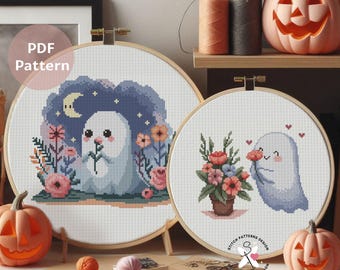 May include: Two cross-stitch patterns in wooden hoops, featuring cute ghost designs with flowers. One ghost holds a flower, the other is surrounded by a floral arrangement. The words "PDF Pattern" are visible. Pumpkins and craft supplies are in the background.