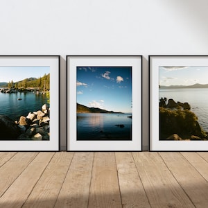 May include: Three framed photographs of a lake with mountains in the background. The first photo shows a rocky shoreline with trees in the distance. The second photo shows a wider view of the lake with a blue sky and clouds. The third photo shows a close-up of the rocky shoreline with the lake in the background.