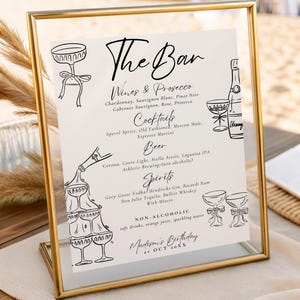 Pode incluir: Uma placa dourada com as palavras "The Bar" em escrita elegante. A placa lista vinhos, cocktails, cerveja, bebidas espirituosas e bebidas não alcoólicas. A placa é para o aniversário de Madison, 21 de outubro.