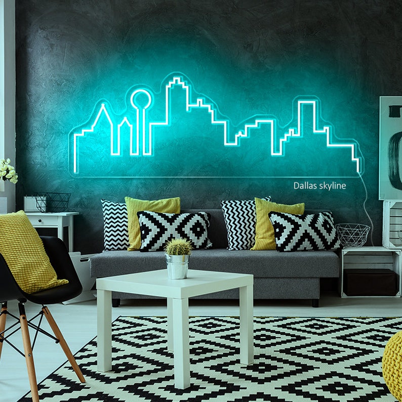 Pu&ograve; includere: Un'insegna al neon turchese raffigurante lo skyline di Dallas &egrave; montata su una parete grigio scuro. L'insegna illumina un soggiorno con un divano grigio, cuscini decorativi e un tappeto a motivi bianchi e neri. Il testo "Dallas skyline" &egrave; sotto.