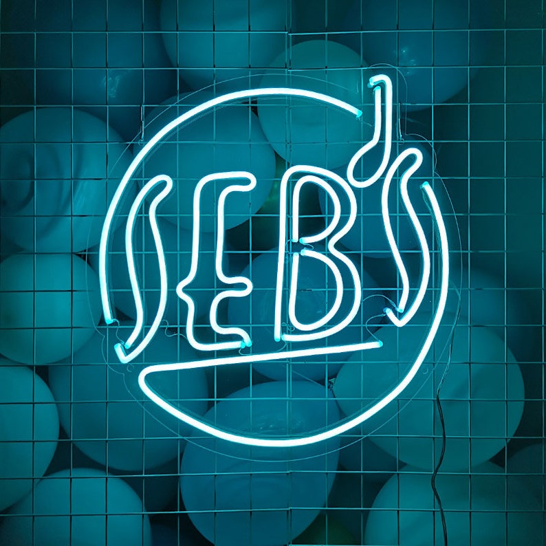 Peut inclure: Un panneau lumineux n&eacute;on avec le mot "SEB's" dans un cercle, entour&eacute; de ballons bleus.