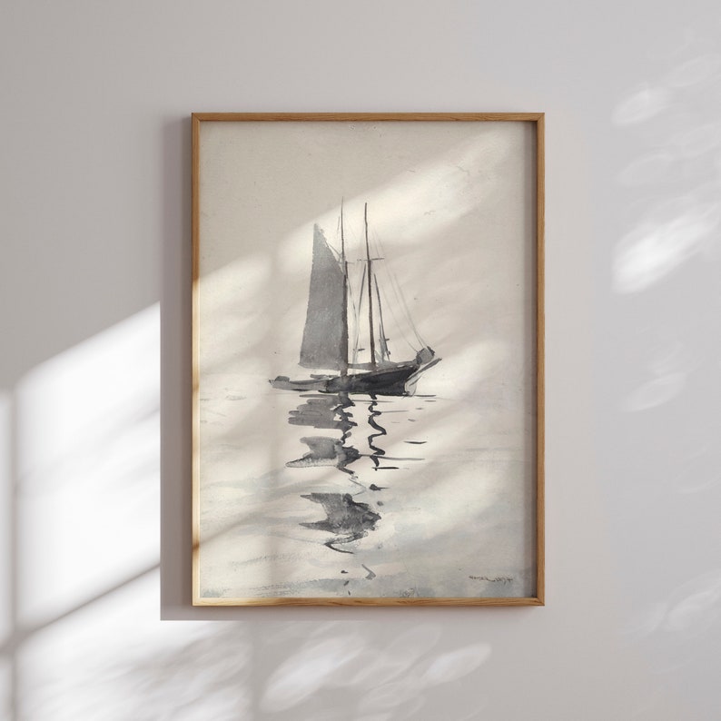 Op de afbeelding: Een ingelijste aquarel van een zeilboot op kalm water. Het kunstwerk is voornamelijk in grijstinten en zwart, met de boot en zijn weerspiegeling duidelijk zichtbaar. De lijst is gemaakt van lichtgekleurd hout, wat een klassieke touch geeft aan het nautische thema.