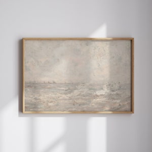 Op de afbeelding: Een ingelijst landschapsschilderij met een gedempt kleurenpalet. Het kunstwerk toont een zeegezicht met een bewolkte lucht en woelig water. De lijst is gemaakt van lichtgekleurd hout, wat een natuurlijke toets aan het stuk geeft.