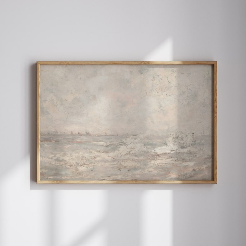 Op de afbeelding: Een ingelijst landschapsschilderij met een gedempt kleurenpalet. Het kunstwerk toont een zeegezicht met een bewolkte lucht en woelig water. De lijst is gemaakt van lichtgekleurd hout, wat een natuurlijke toets aan het stuk geeft.