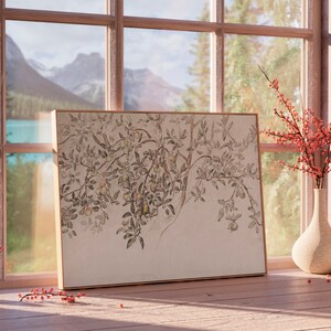 May include: A framed print of a black and white drawing of a tree branch with leaves and fruit. The print is hanging on a wall next to a window with a view of a lake and mountains. There are red berries in a vase on a table in front of the print.