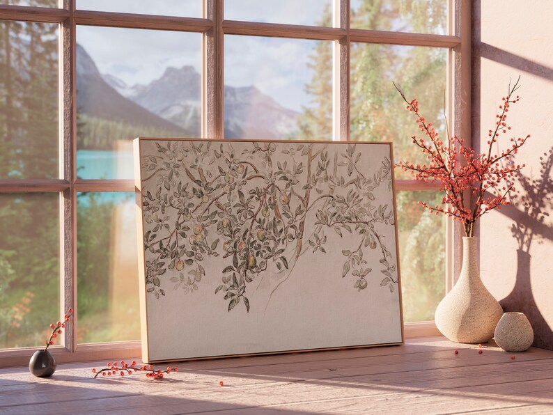 May include: A framed print of a black and white drawing of a tree branch with leaves and fruit. The print is hanging on a wall next to a window with a view of a lake and mountains. There are red berries in a vase on a table in front of the print.