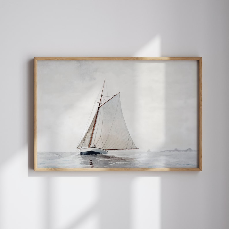 Op de afbeelding: Waterverfschilderij van een zeilboot op het water, ingelijst in licht hout. De boot heeft een wit zeil en een donkerblauwe romp. De lucht is bewolkt en het water is een gedempt blauw.