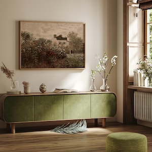 K&ouml;nnte beinhalten: Ein gerahmtes Landschaftsgem&auml;lde h&auml;ngt &uuml;ber einem gr&uuml;nen Samtschrank. Das Gem&auml;lde zeigt ein Haus, das von B&auml;umen und Blumen umgeben ist. Vasen mit Blumen und ein dekoratives Objekt stehen auf dem Schrank. Ein gr&uuml;ner Hocker befindet sich im Vordergrund.