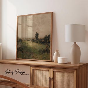 May include: A framed landscape art print with a wooden frame. The artwork depicts a field with green grass and trees under a cloudy sky. The print is displayed on a wooden cabinet with a lamp and decorative vases. The text "Gate of Design STUDIO" is visible.