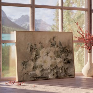 May include: A framed painting of a bouquet of white flowers with green leaves, set against a backdrop of a mountain landscape seen through a window. The painting is on a wooden table with a vase of red berries and a small vase.