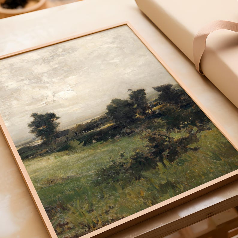 May include: A framed painting of a landscape with a field of green grass, trees, and a cloudy sky. The painting is in a light wood frame.
