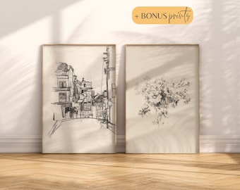 May include: Two framed black and white pencil drawings. The first drawing depicts a street scene with buildings and a street lamp. The second drawing depicts a cluster of flowers.