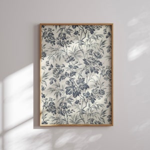 Op de afbeelding: Een ingelijste print met een gedetailleerd bloemenpatroon in blauw en wit. Het ontwerp bevat bloemen, bladeren en bamboestengels tegen een lichte achtergrond. De print is ingelijst in een natuurlijke houten lijst, voor een klassieke uitstraling.