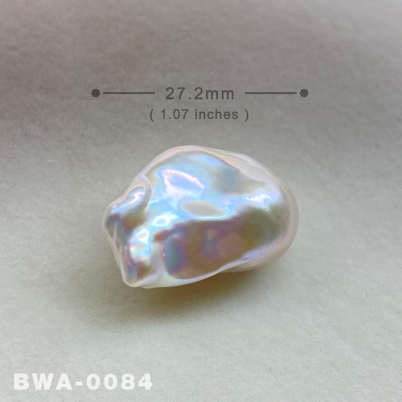May include: A large, iridescent white baroque pearl measuring 27.2 mm (1.07 inches) in diameter. The pearl has an irregular shape with a smooth, glossy surface.