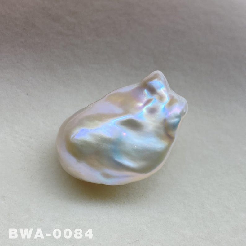 May include: A large, white baroque pearl with iridescent colors. The pearl has an irregular shape and a smooth, glossy surface.