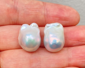 May include: Two large, white baroque pearls with iridescent hues. The pearls are irregularly shaped and have a smooth, glossy finish.