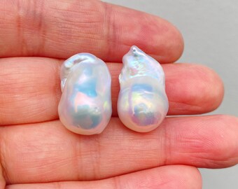 May include: Two large, white baroque pearls with iridescent hues. The pearls are irregular in shape and have a smooth, glossy surface.