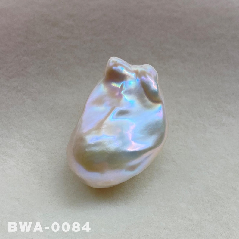 May include: A large, iridescent white baroque pearl with a unique, irregular shape. The pearl has a smooth, glossy surface and a subtle, pearlescent sheen.